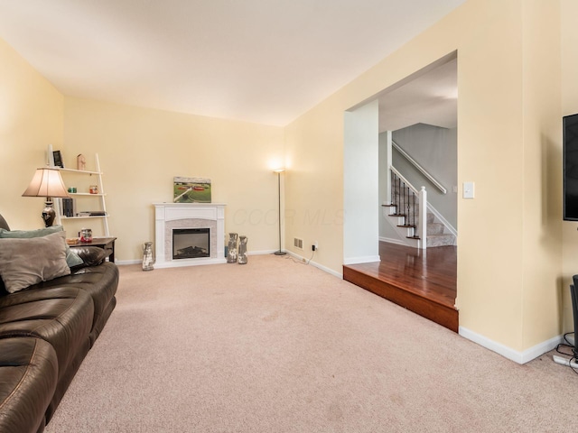 living room featuring a fireplace, stairs, baseboards, and carpet floors