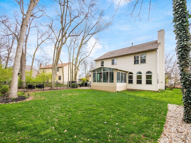 back of house with a sunroom, a chimney, fence, and a lawn