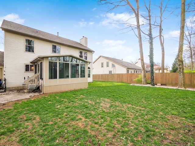 back of property with a sunroom, a chimney, fence, and a lawn