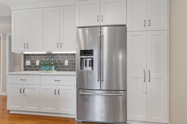 kitchen featuring light countertops, backsplash, white cabinets, and high quality fridge