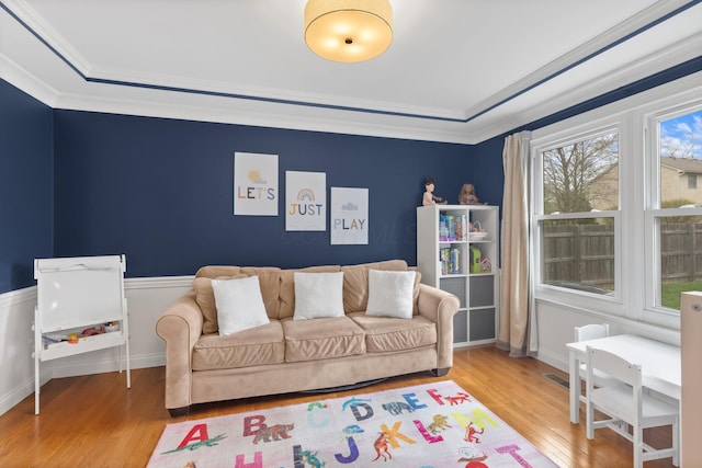 interior space with a raised ceiling, wood finished floors, and ornamental molding
