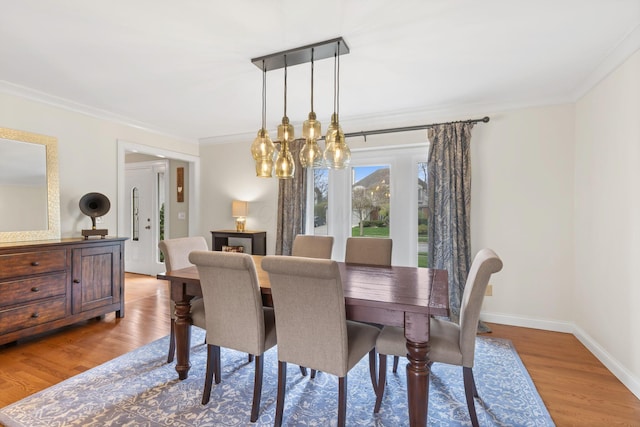 dining space with a chandelier, wood finished floors, and ornamental molding