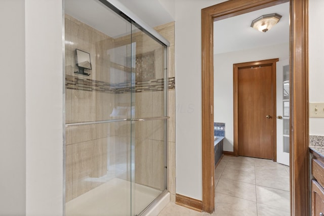 bathroom with tile patterned floors, a stall shower, baseboards, a garden tub, and vanity
