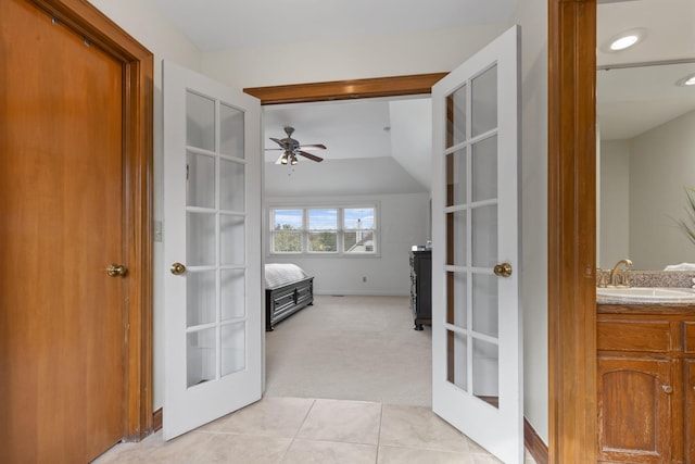 corridor with light carpet, french doors, a sink, light tile patterned flooring, and lofted ceiling