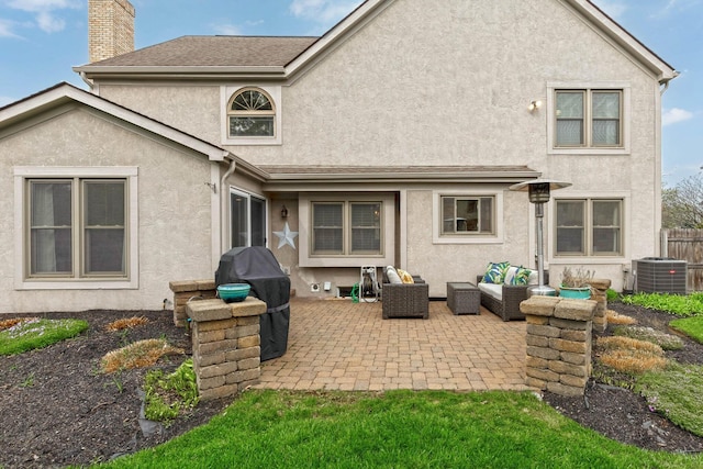 rear view of house featuring stucco siding, an outdoor living space, and a patio area