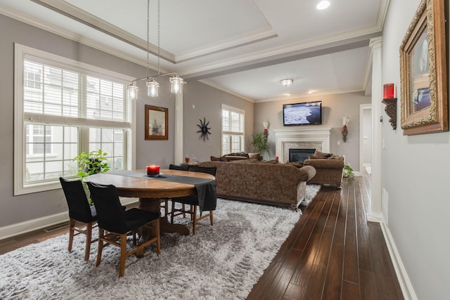dining area featuring ornamental molding, baseboards, a premium fireplace, and dark wood finished floors