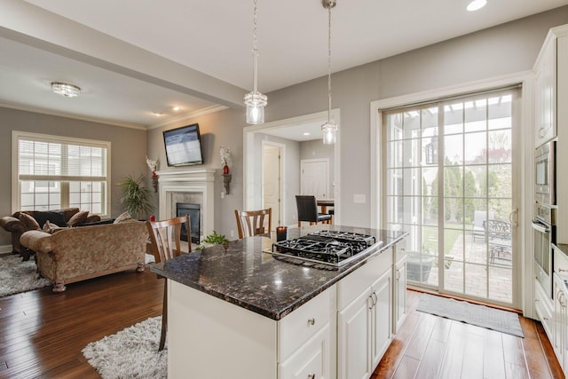 kitchen with white cabinetry, ornamental molding, stainless steel appliances, a tile fireplace, and dark wood-style floors