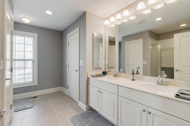 full bathroom featuring baseboards, a sink, double vanity, tile patterned flooring, and a stall shower
