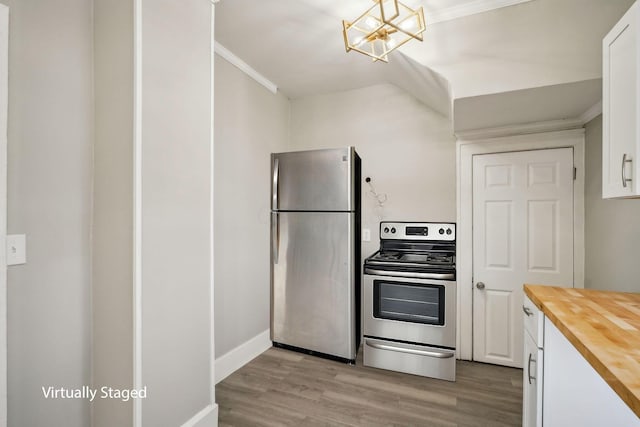 kitchen featuring light wood-style flooring, butcher block counters, appliances with stainless steel finishes, white cabinets, and ornamental molding