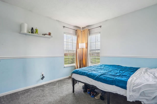 carpeted bedroom featuring a textured ceiling and baseboards