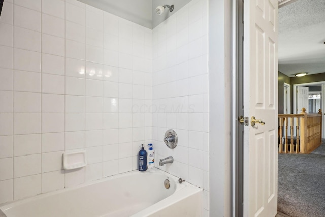 full bathroom with a textured ceiling and  shower combination
