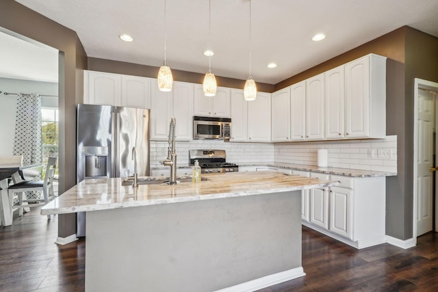 kitchen with dark wood-style floors, appliances with stainless steel finishes, light stone counters, and white cabinetry