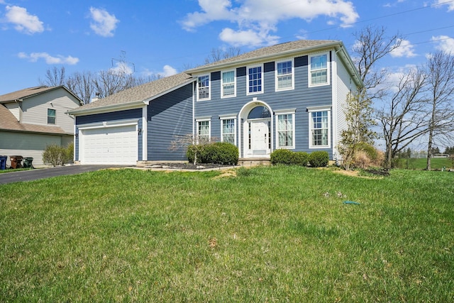 colonial inspired home with a front yard, an attached garage, and aphalt driveway