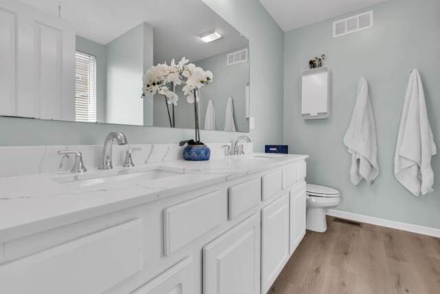 bathroom featuring toilet, a sink, and visible vents
