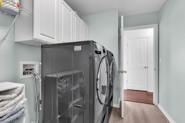 laundry room featuring cabinet space, washer and clothes dryer, light wood finished floors, and baseboards