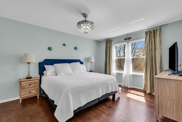 bedroom with dark wood-style flooring, baseboards, and an inviting chandelier