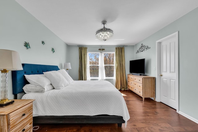 bedroom with a chandelier, baseboards, and dark wood finished floors