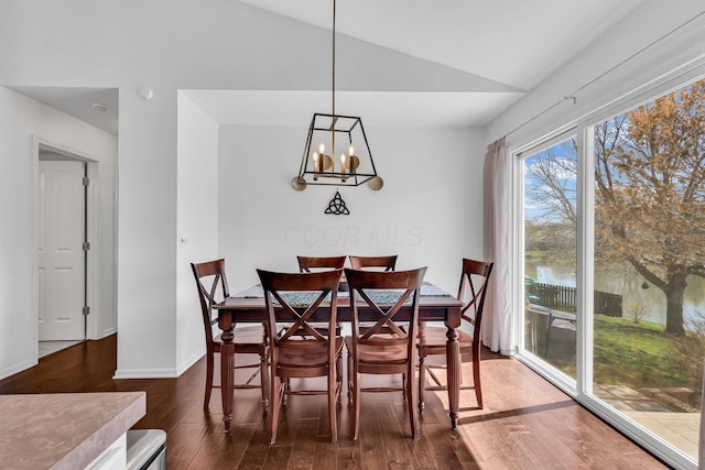 dining space featuring dark wood-style flooring, baseboards, a notable chandelier, and lofted ceiling