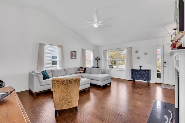 living area with baseboards, ceiling fan, a fireplace with flush hearth, dark wood-type flooring, and high vaulted ceiling
