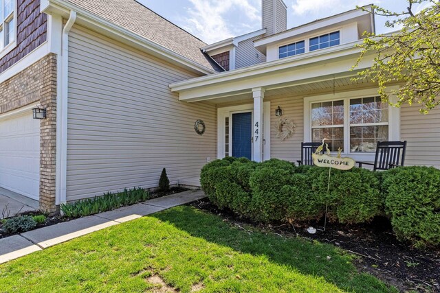 view of exterior entry with a porch and a garage