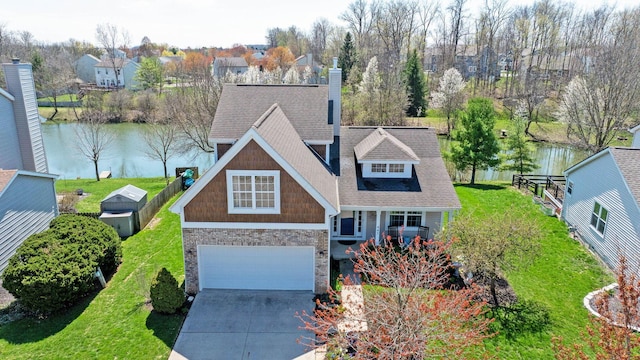 view of front facade featuring a water view, concrete driveway, a front yard, a garage, and a shingled roof