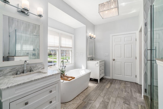 bathroom featuring a sink, two vanities, a shower stall, and wood finished floors