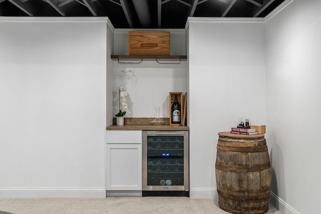 bar featuring a bar, baseboards, beverage cooler, and carpet floors