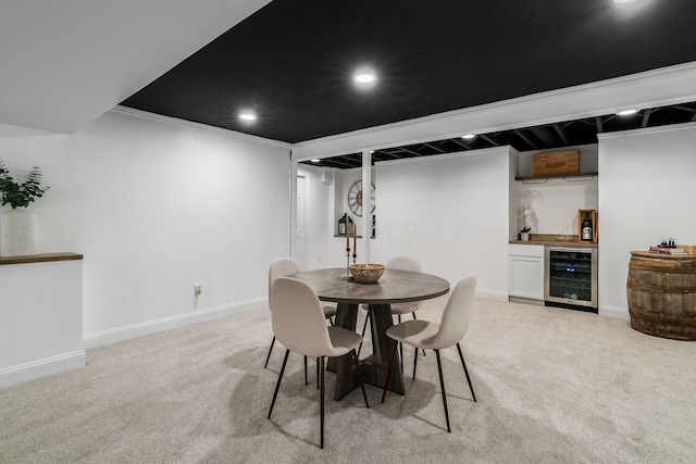 dining area featuring light carpet, baseboards, beverage cooler, and indoor bar
