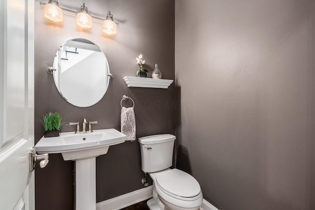 bathroom featuring toilet, a sink, and baseboards