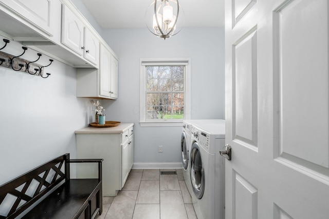clothes washing area with light tile patterned floors, washer and clothes dryer, baseboards, cabinet space, and a notable chandelier