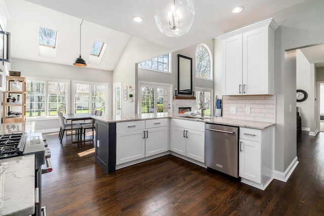 kitchen with appliances with stainless steel finishes, light stone counters, a peninsula, decorative backsplash, and a sink