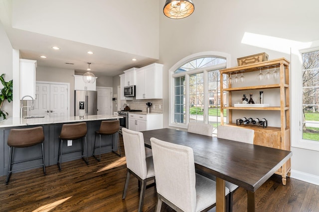 dining space with baseboards, recessed lighting, a towering ceiling, and dark wood finished floors