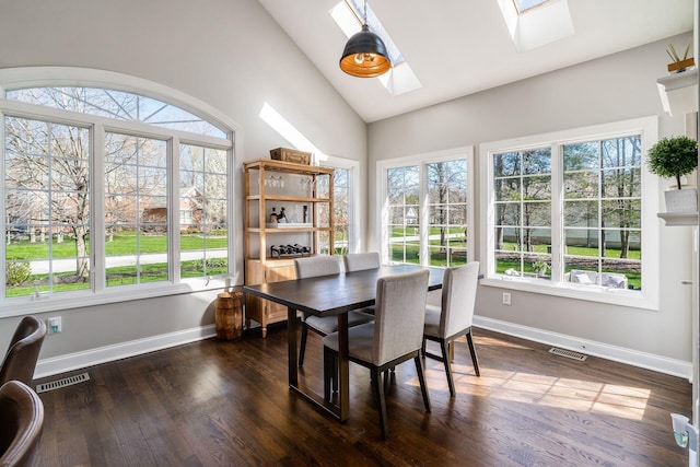 dining space with dark wood-type flooring, vaulted ceiling with skylight, baseboards, and visible vents