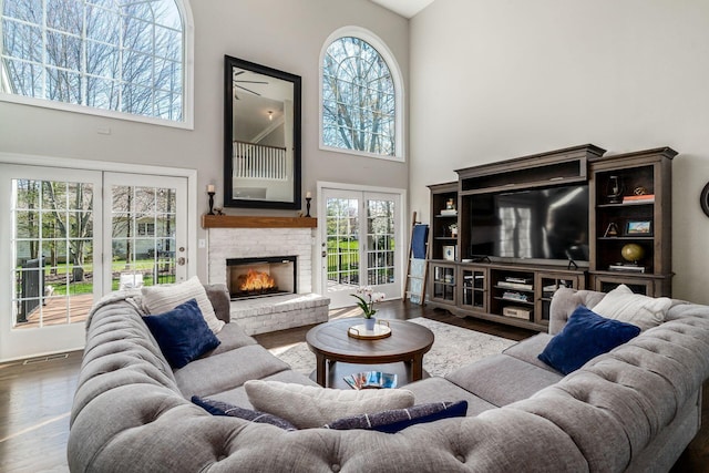 living room with visible vents, a towering ceiling, wood finished floors, and a fireplace