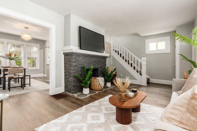 1069 Miller Ave, Columbus, OH 43206 - living room featuring stairway, baseboards, wood finished floors, a fireplace, and a chandelier
