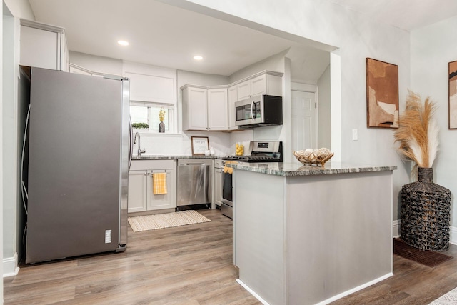 1069 Miller Ave, Columbus, OH 43206 - kitchen featuring stainless steel appliances, light wood-type flooring, light stone counters, a peninsula, and recessed lighting