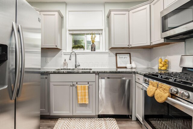 1069 Miller Ave, Columbus, OH 43206 - kitchen with stainless steel appliances, a sink, dark stone countertops, and backsplash
