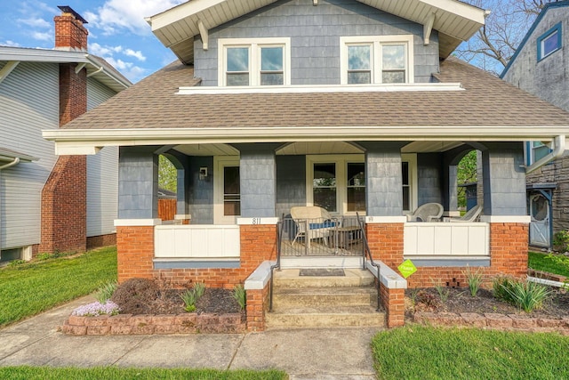 bungalow-style house with a porch and roof with shingles