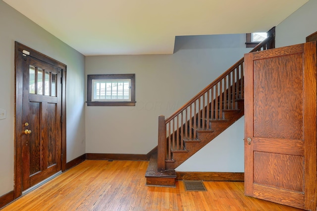 entrance foyer with baseboards, visible vents, hardwood / wood-style flooring, and stairway