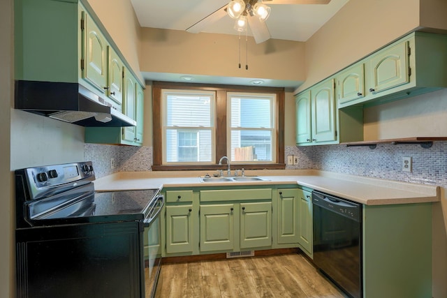 kitchen featuring green cabinetry, a sink, under cabinet range hood, visible vents, and black appliances