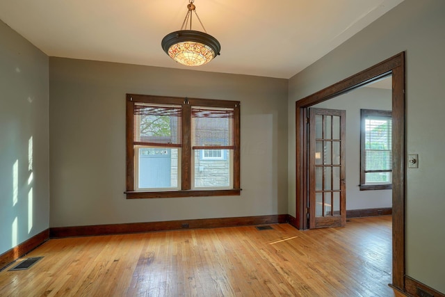 spare room with visible vents, light wood finished floors, and baseboards