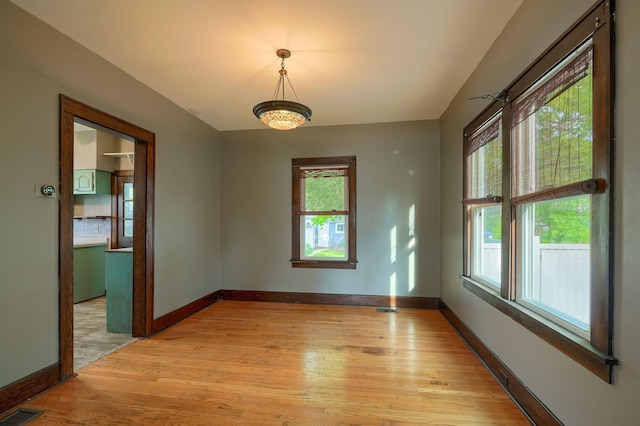 empty room featuring light wood-type flooring, baseboards, and visible vents