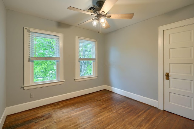unfurnished room with baseboards, dark wood finished floors, ceiling fan, and visible vents