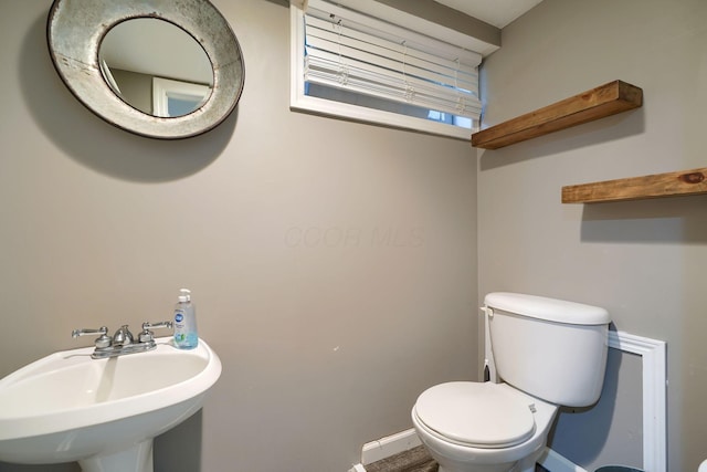 bathroom with toilet, baseboards, and a sink