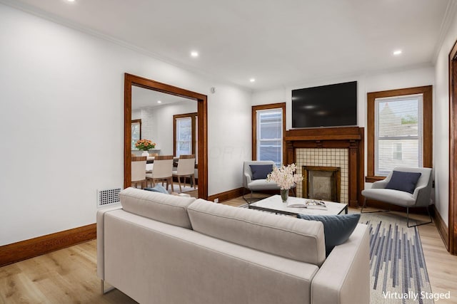 1065-1067 Franklin Ave, Columbus, OH 43205 - living area featuring baseboards, light wood-style floors, recessed lighting, a tiled fireplace, and crown molding