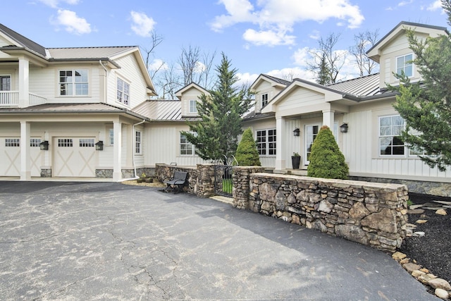 view of front of home featuring a standing seam roof, aphalt driveway, metal roof, fence, and a garage