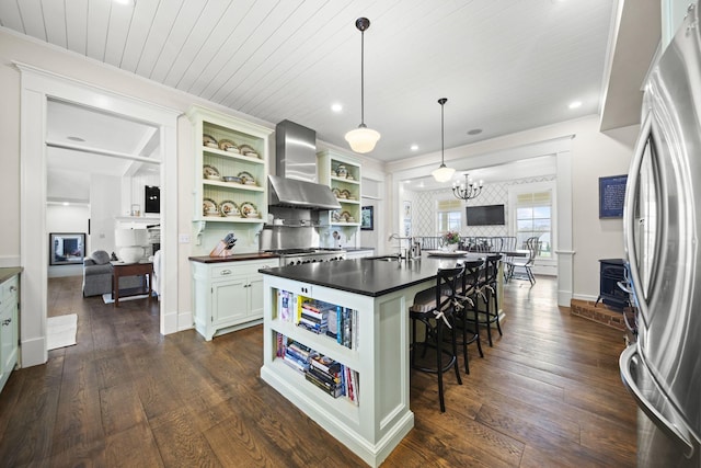 kitchen with open shelves, wall chimney exhaust hood, dark countertops, freestanding refrigerator, and recessed lighting