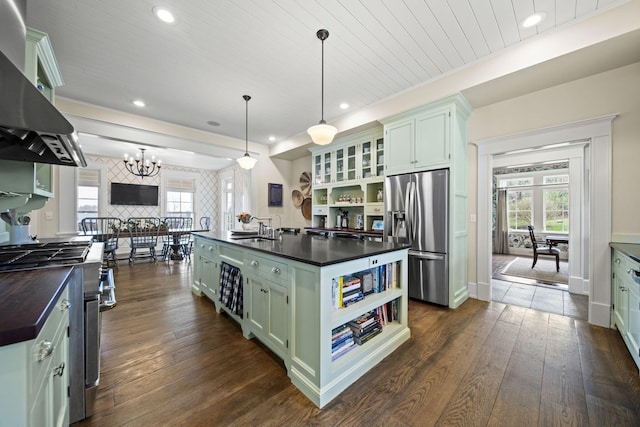 kitchen with green cabinets, open shelves, appliances with stainless steel finishes, range hood, and a sink
