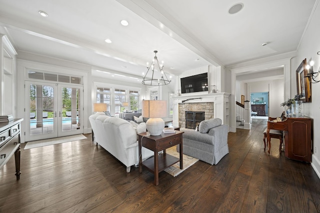 living room with a notable chandelier, a fireplace, crown molding, dark wood-style floors, and french doors