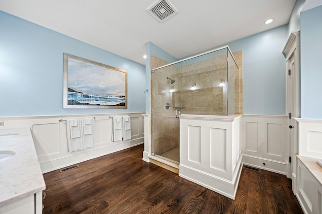 full bath with a decorative wall, visible vents, a shower stall, and wainscoting